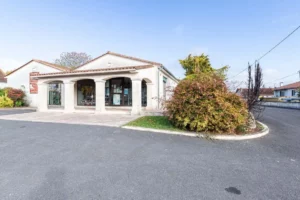 Entrée de l'agence de pompes funèbres avec piliers et espace vert.