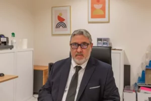 Conseiller funéraire en costume noir assis à son bureau en agence.